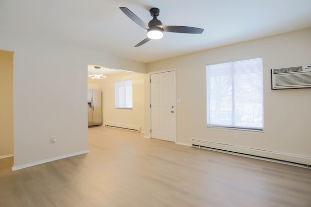 empty room featuring ceiling fan, a wall mounted AC, baseboard heating, and light hardwood / wood-style floors