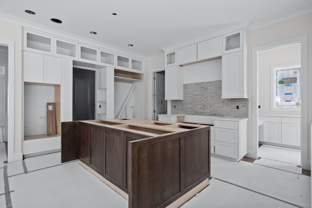 kitchen with decorative backsplash, white cabinetry, and ornamental molding