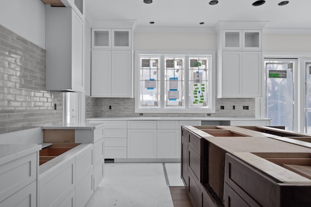 kitchen featuring decorative backsplash, white cabinetry, and ornamental molding