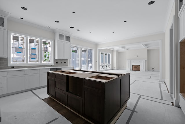 kitchen featuring white cabinets, decorative backsplash, crown molding, and a kitchen island