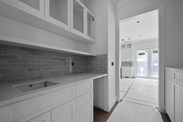 kitchen featuring white cabinetry, decorative backsplash, and ornamental molding