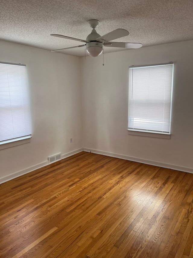 unfurnished room featuring hardwood / wood-style flooring, plenty of natural light, a textured ceiling, and ceiling fan