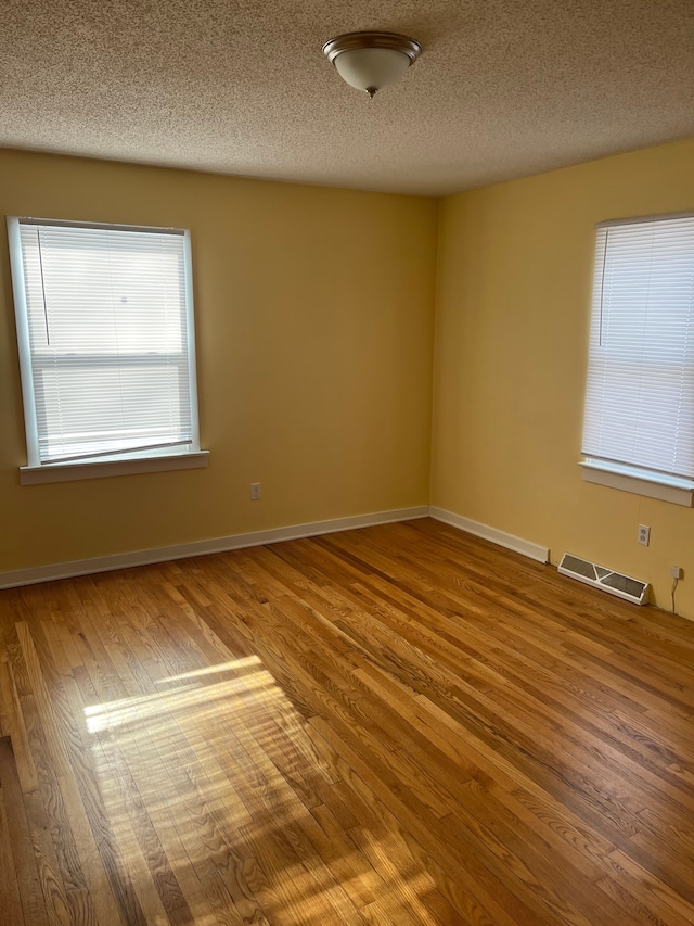 unfurnished room with hardwood / wood-style flooring and a textured ceiling