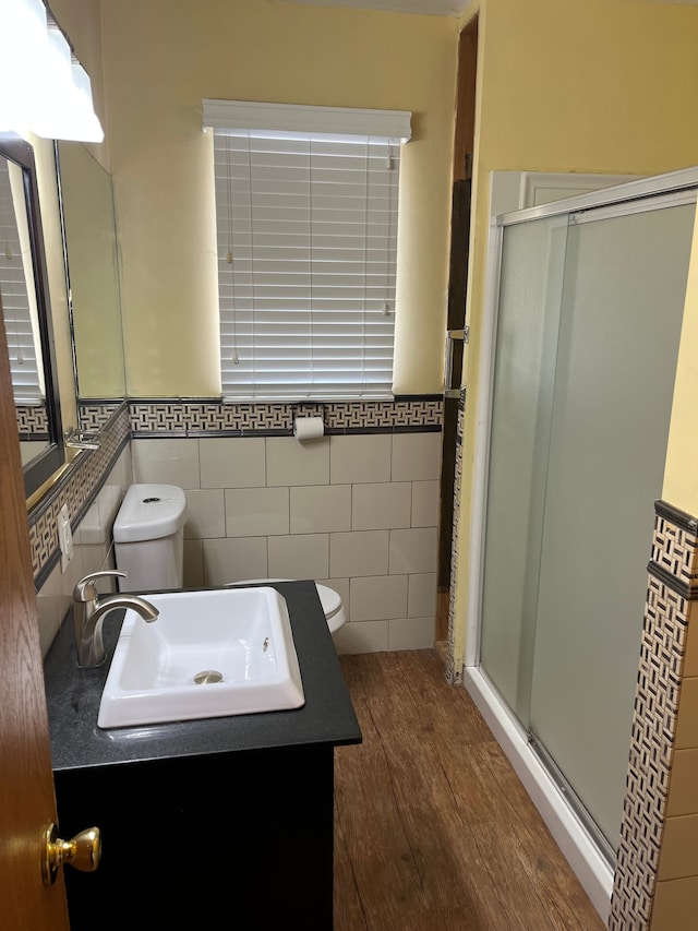 bathroom featuring toilet, tile walls, a shower with door, and hardwood / wood-style floors