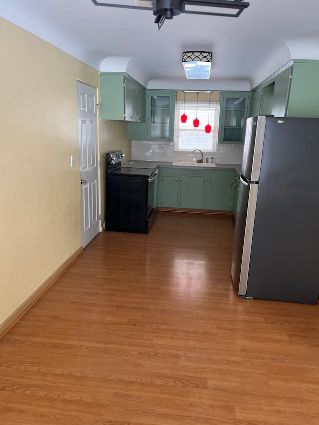 kitchen with stainless steel refrigerator, green cabinetry, black range with electric cooktop, light hardwood / wood-style flooring, and sink