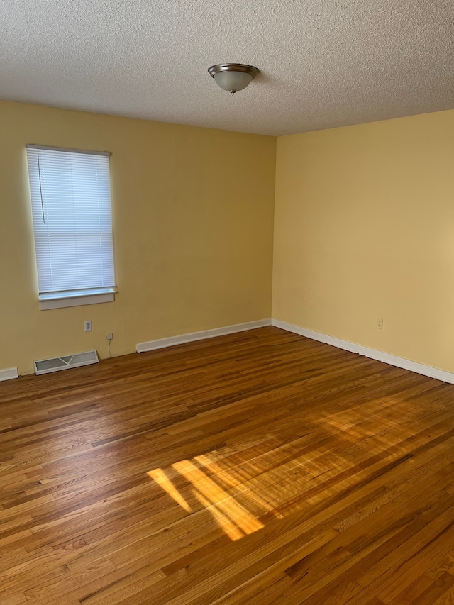 empty room with wood-type flooring and a textured ceiling