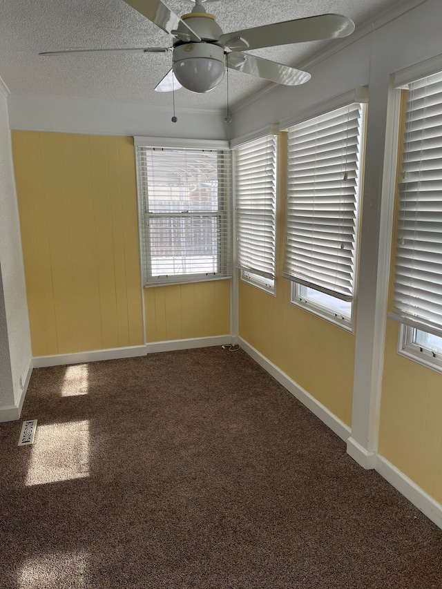 empty room featuring a textured ceiling, ceiling fan, and carpet