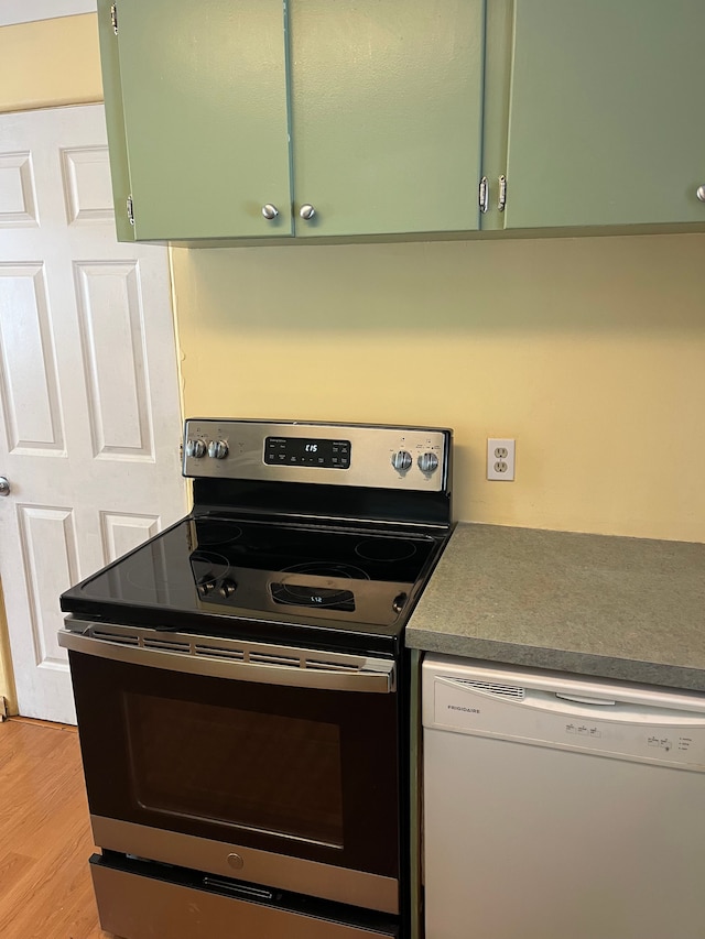 kitchen with electric stove, white dishwasher, green cabinetry, and light hardwood / wood-style floors