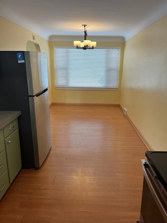 kitchen with appliances with stainless steel finishes, light wood-type flooring, hanging light fixtures, green cabinetry, and a chandelier