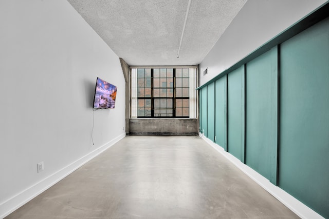 unfurnished room with a textured ceiling and concrete flooring