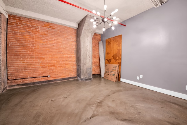 unfurnished living room with brick wall, a textured ceiling, a chandelier, and concrete flooring