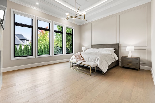 bedroom with light wood-type flooring, ornamental molding, a chandelier, and a raised ceiling