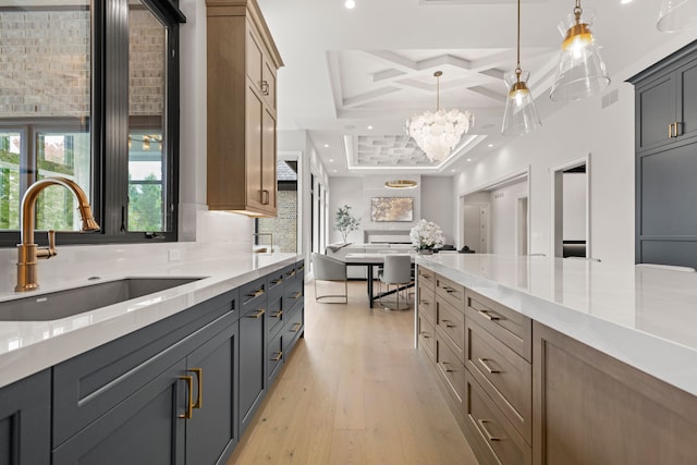 kitchen with light hardwood / wood-style flooring, sink, hanging light fixtures, and coffered ceiling