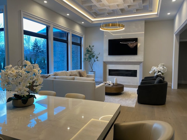 living room with coffered ceiling, a high end fireplace, and hardwood / wood-style floors