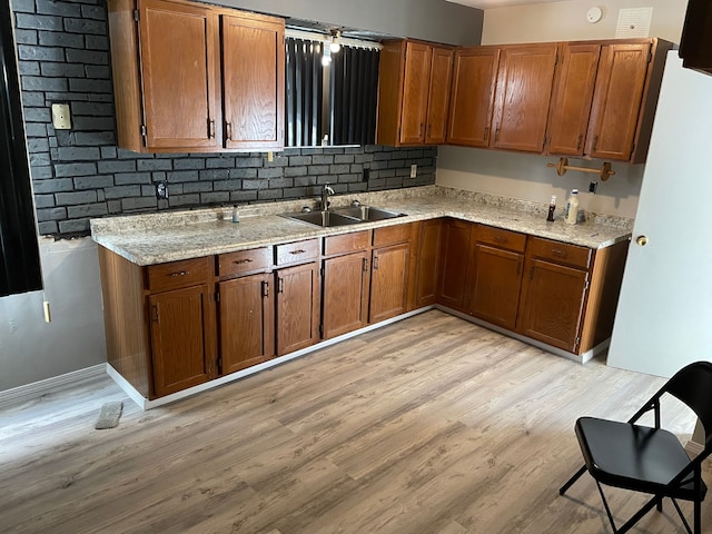 kitchen with decorative backsplash, light hardwood / wood-style floors, light stone counters, and sink