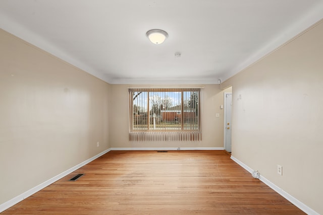 spare room with crown molding and light wood-type flooring