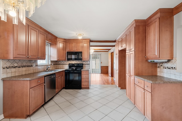 kitchen featuring sink, light tile patterned floors, black appliances, and stone countertops