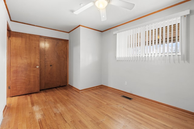 unfurnished bedroom with crown molding, ceiling fan, light hardwood / wood-style floors, and a closet