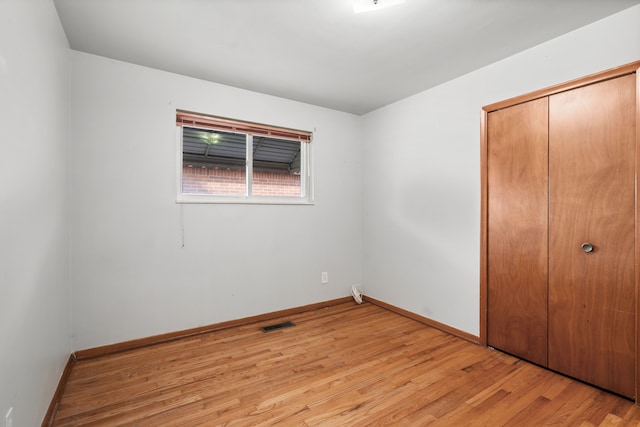 unfurnished bedroom with light wood-type flooring and a closet