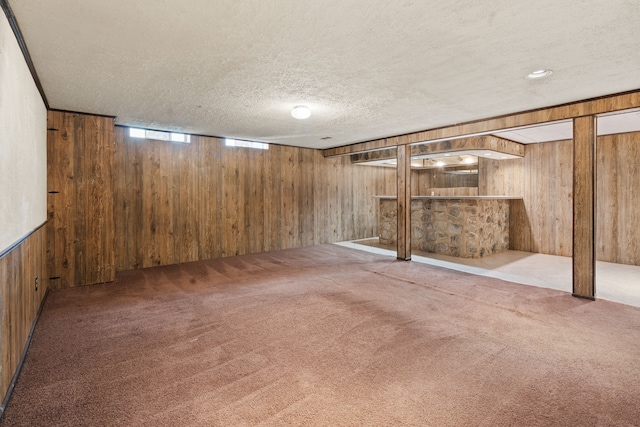 basement with carpet flooring, a textured ceiling, and wood walls