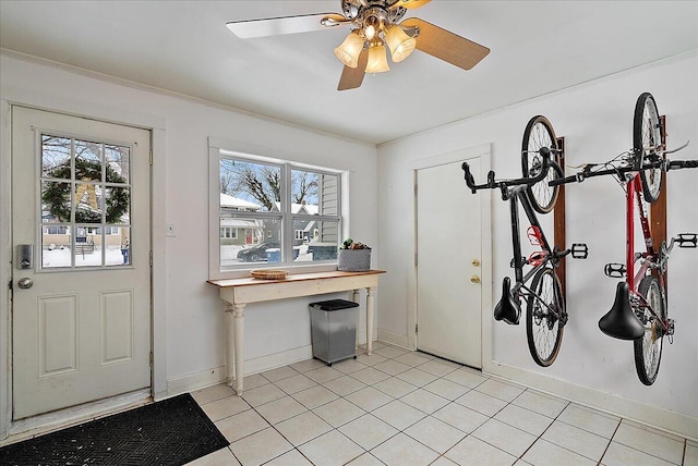 interior space with ceiling fan, crown molding, and light tile patterned flooring