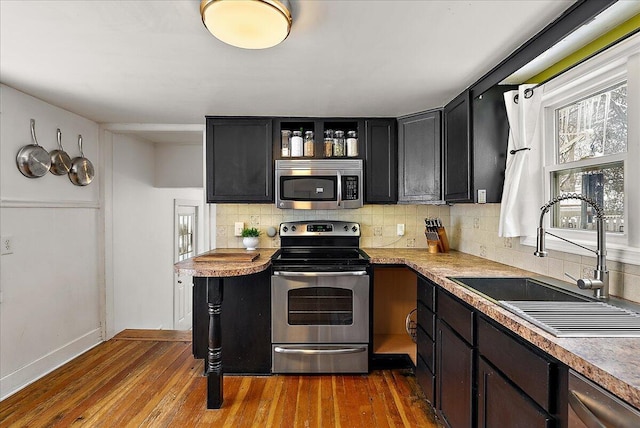 kitchen featuring stainless steel appliances, decorative backsplash, hardwood / wood-style floors, and sink