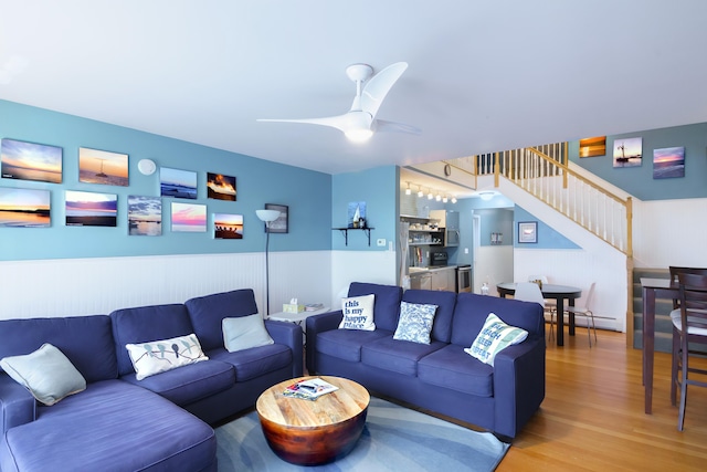 living room featuring a baseboard heating unit, ceiling fan, and wood-type flooring