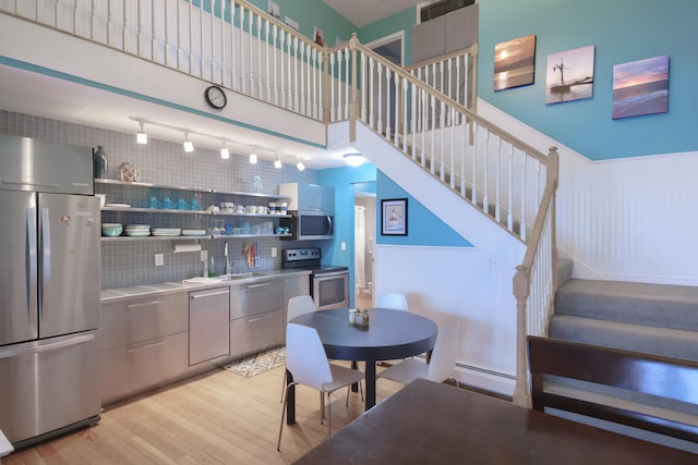 kitchen with light hardwood / wood-style floors, stainless steel appliances, tasteful backsplash, a baseboard radiator, and sink