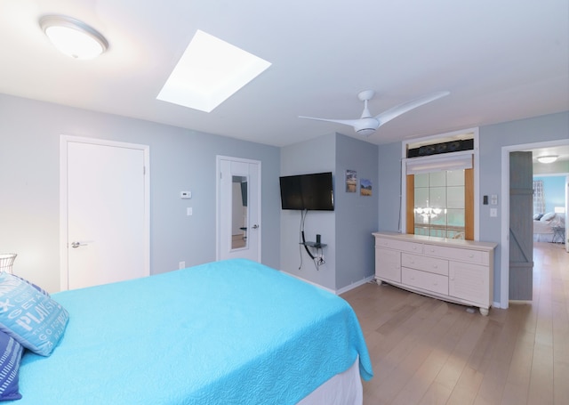 bedroom with ceiling fan, a skylight, and light wood-type flooring