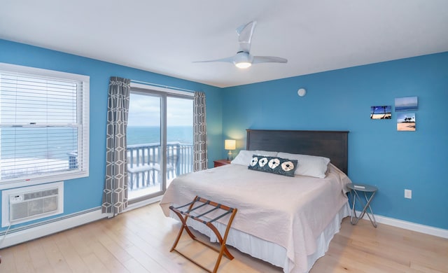 bedroom featuring ceiling fan, light hardwood / wood-style flooring, a wall mounted air conditioner, a water view, and baseboard heating