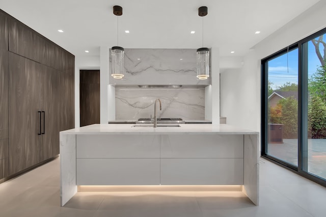 kitchen featuring decorative backsplash, light stone counters, dark brown cabinetry, and decorative light fixtures