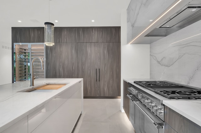 kitchen featuring decorative light fixtures, stainless steel stove, sink, dark brown cabinetry, and light stone countertops