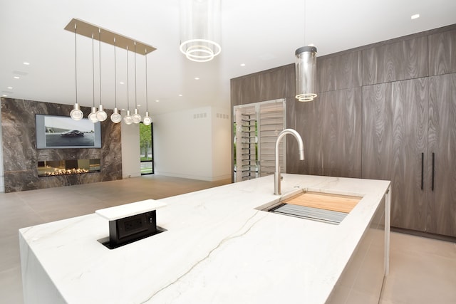 kitchen featuring pendant lighting, a kitchen island with sink, and a premium fireplace