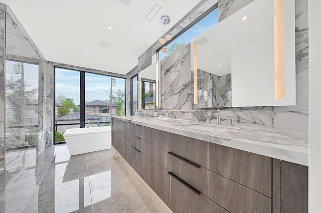 bathroom with floor to ceiling windows, a washtub, vanity, and a healthy amount of sunlight