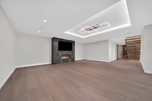 unfurnished living room featuring wood-type flooring and a tiled fireplace