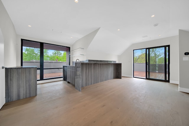 unfurnished living room featuring lofted ceiling, sink, and light hardwood / wood-style floors