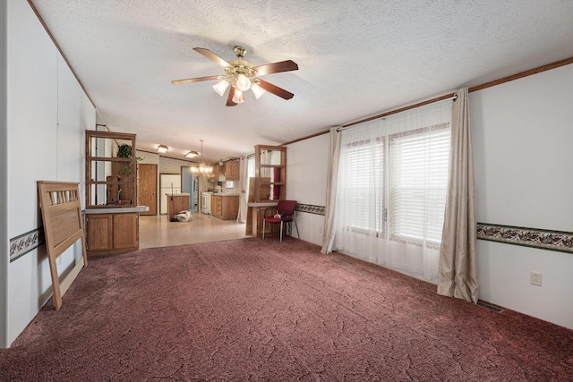 unfurnished living room with a textured ceiling, carpet, and ceiling fan with notable chandelier