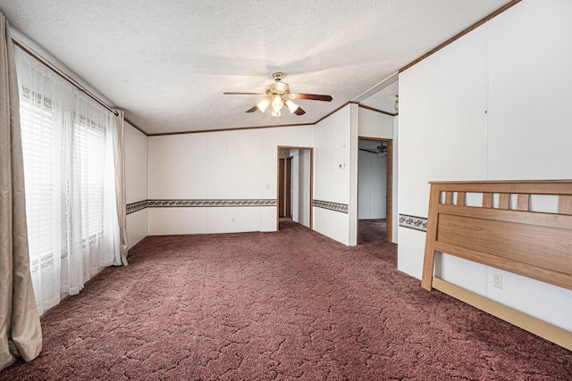 unfurnished bedroom featuring a textured ceiling, ornamental molding, vaulted ceiling, ceiling fan, and dark carpet