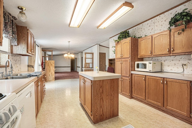 kitchen featuring white appliances, a textured ceiling, a kitchen island, an inviting chandelier, and sink