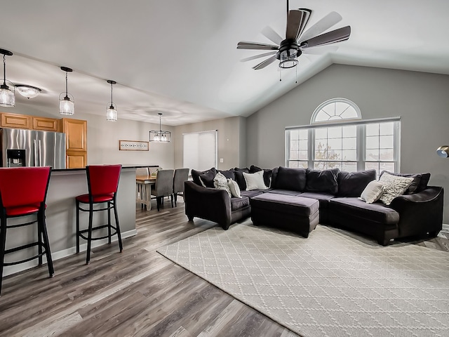 living room featuring lofted ceiling, ceiling fan with notable chandelier, and hardwood / wood-style floors