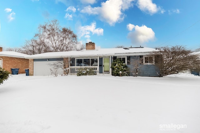 snow covered property with a garage and a porch