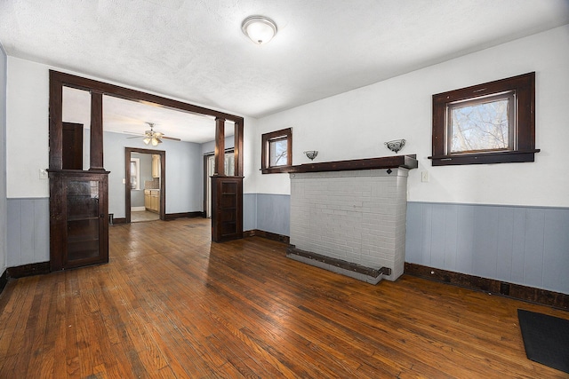 unfurnished living room featuring a textured ceiling, ceiling fan, and dark hardwood / wood-style flooring