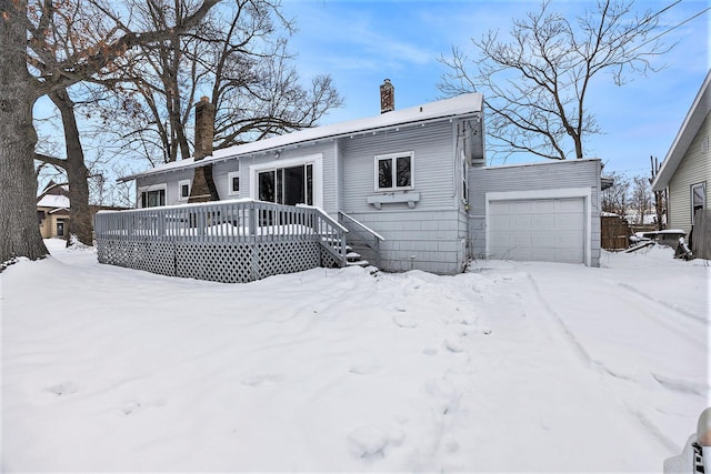 snow covered house featuring a deck and a garage