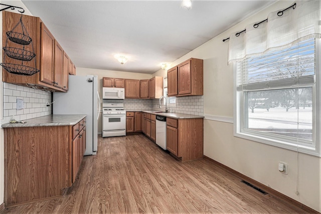 kitchen featuring light hardwood / wood-style floors, sink, white appliances, and tasteful backsplash