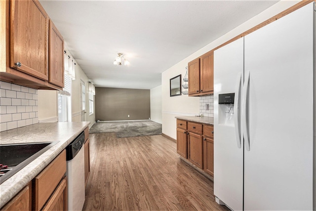 kitchen with light hardwood / wood-style flooring, white fridge with ice dispenser, backsplash, and dishwasher