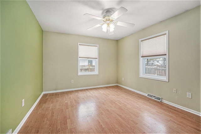 spare room with ceiling fan, light wood-type flooring, and a healthy amount of sunlight