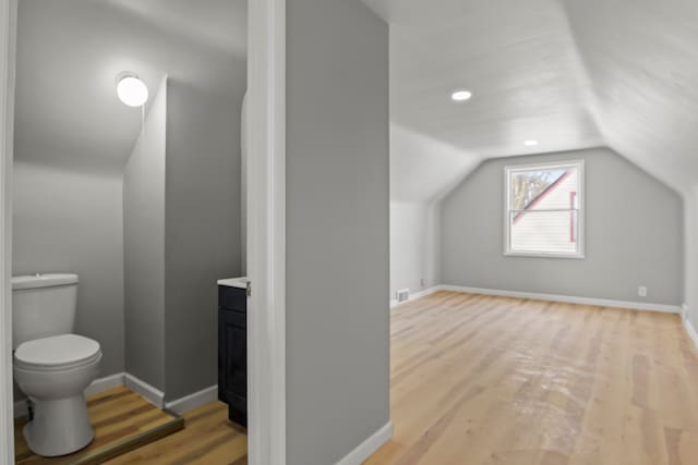 additional living space with vaulted ceiling and light hardwood / wood-style floors