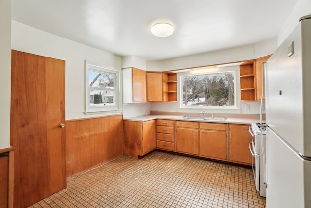 kitchen featuring sink, white appliances, and wooden walls