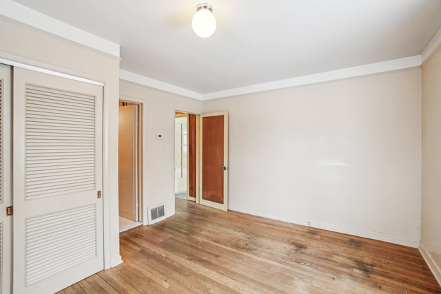 unfurnished bedroom featuring hardwood / wood-style floors, a closet, and ornamental molding