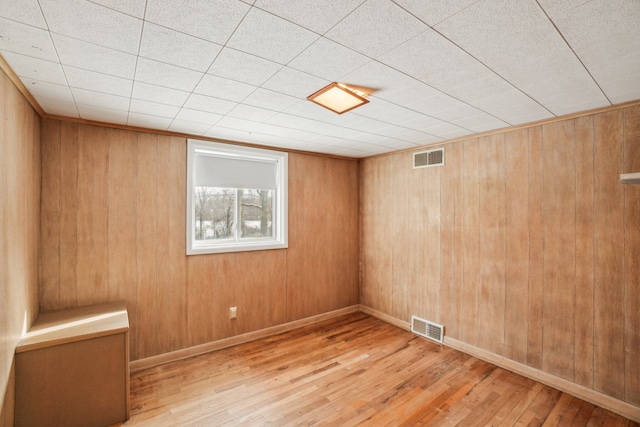 unfurnished room featuring light hardwood / wood-style floors and wood walls